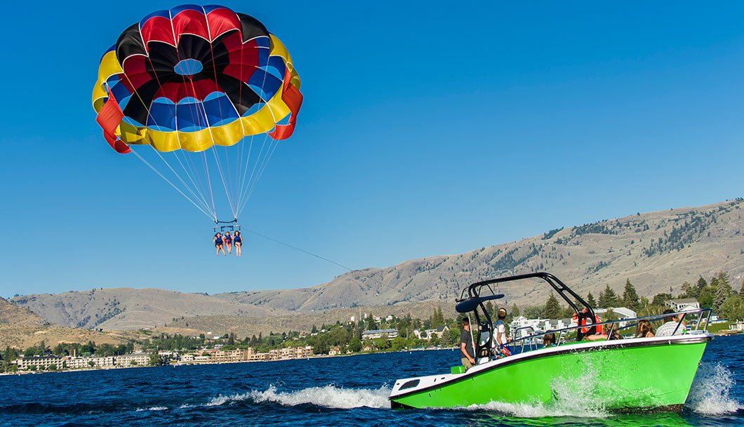 Colorful red blue yellow and black parasail parachute flying in clear blue sky at Lake Chelan